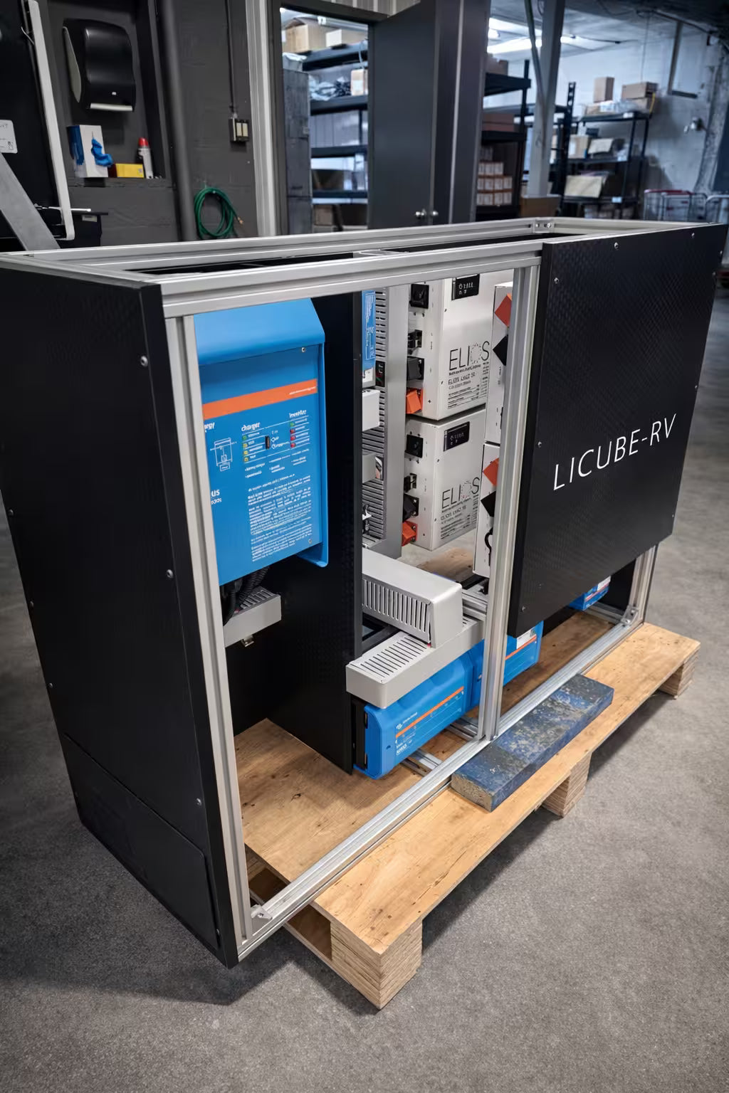 Li-Cube RV Portable Power System equipment cabinet open in a warehouse, showing Victron inverter and Elios components on a wooden pallet