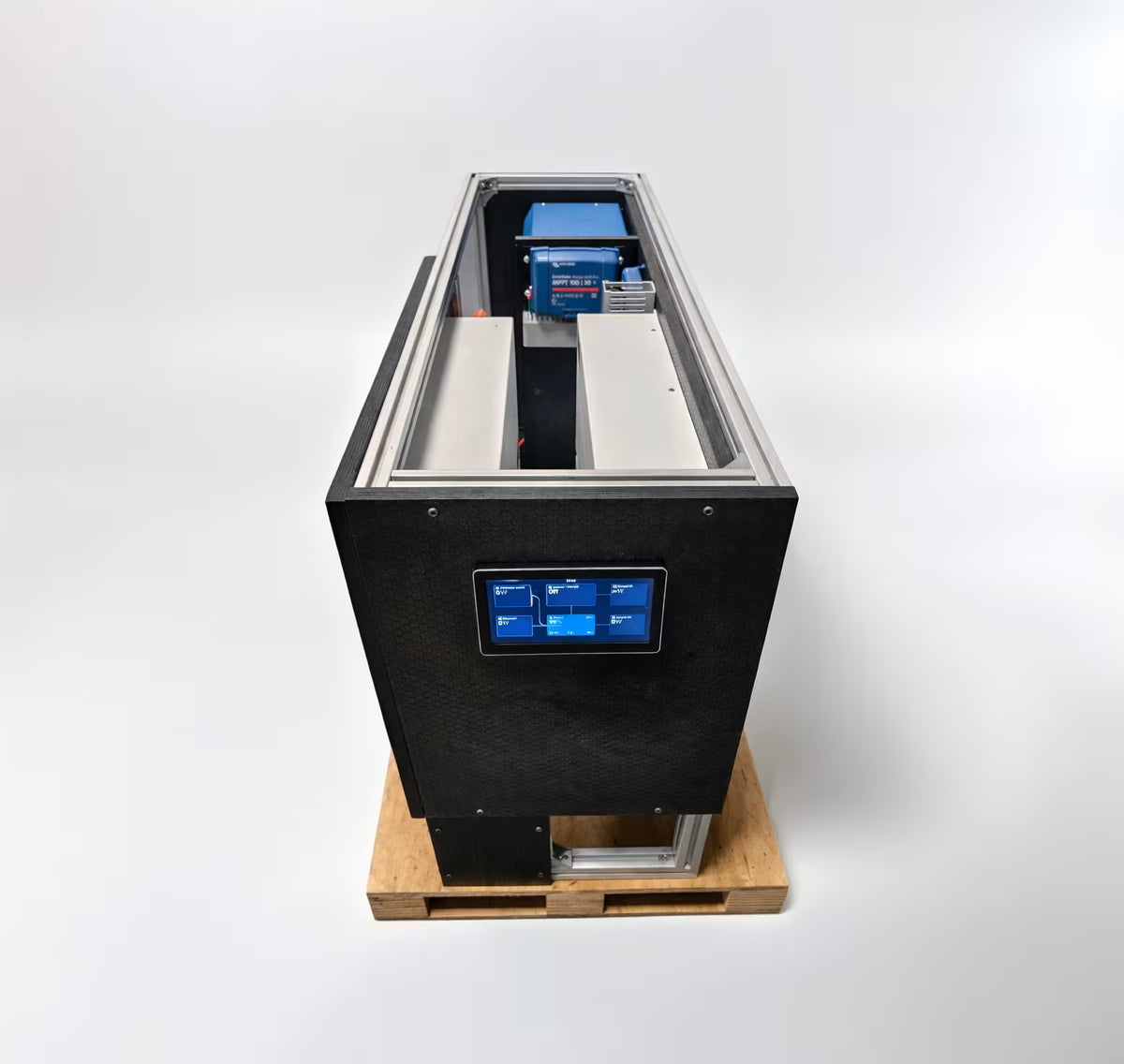 A large black industrial machine with a digital control screen on the front, shown sitting on a wooden pallet against a clean white studio background.